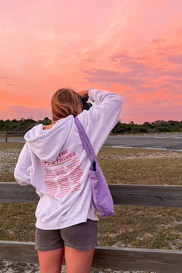 Person taking a photo of a sunset over a field with a wooden fence.