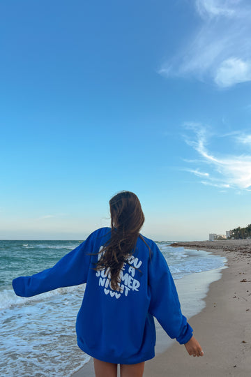 Person wearing a blue sweatshirt with text on the beach